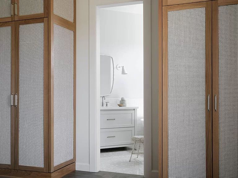 A bathroom with a sink , mirror , and wicker cabinets.