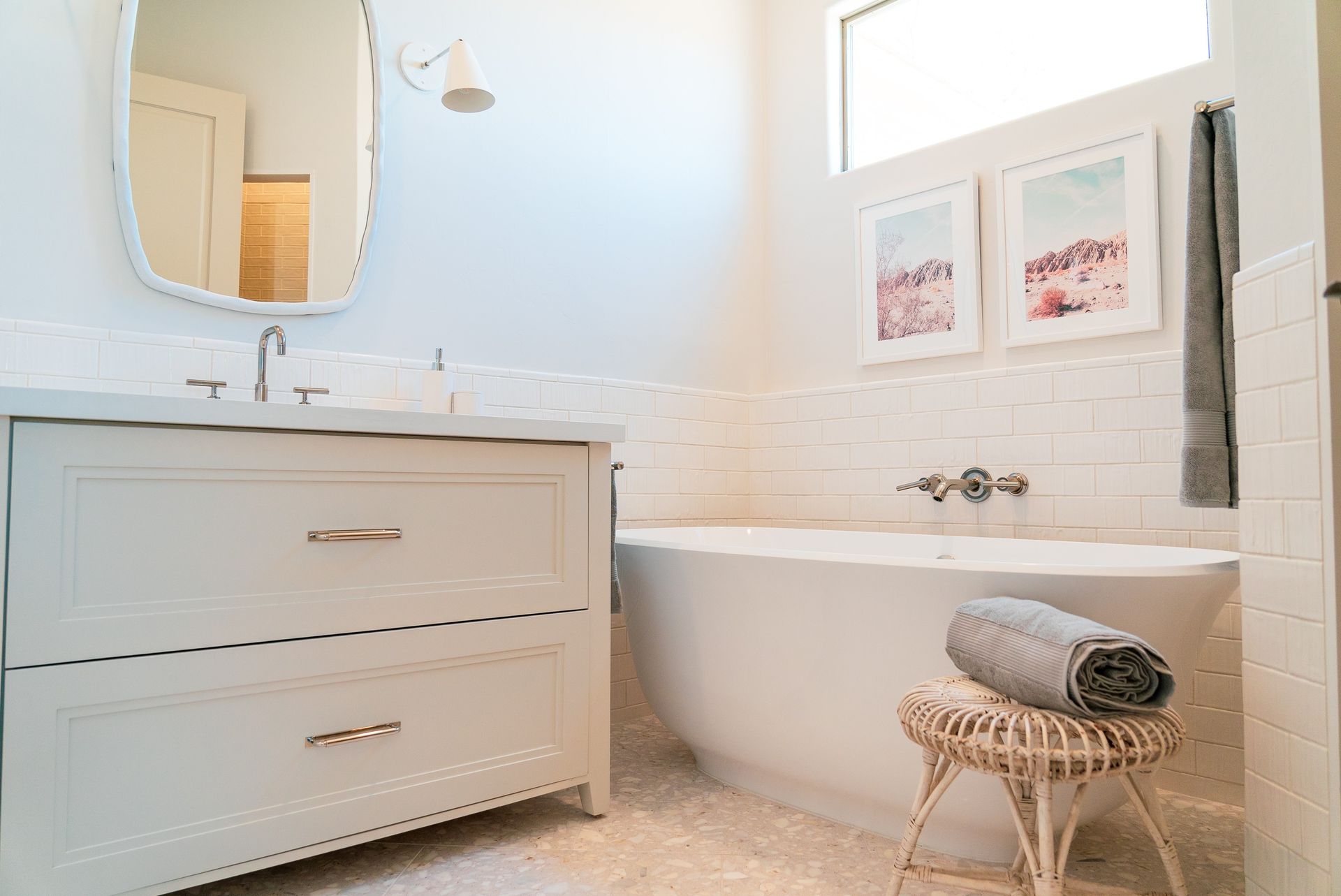 A bathroom with a tub , sink , mirror and stool.