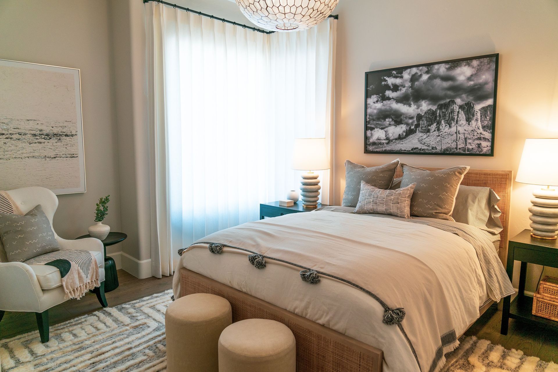 A bedroom with a bed , chair , nightstand , lamps and a painting on the wall.