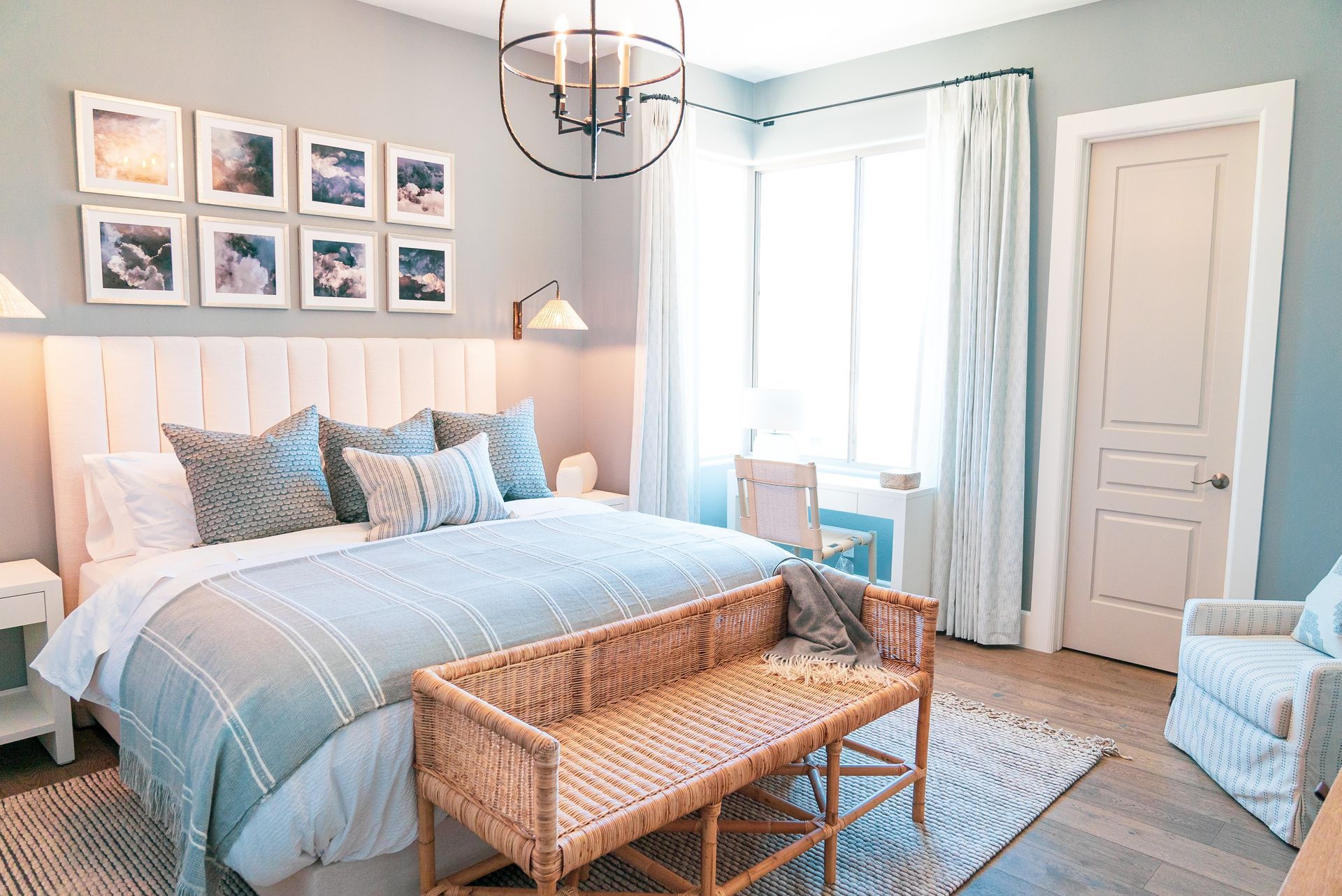 A bedroom with a large bed , wicker bench and chair.