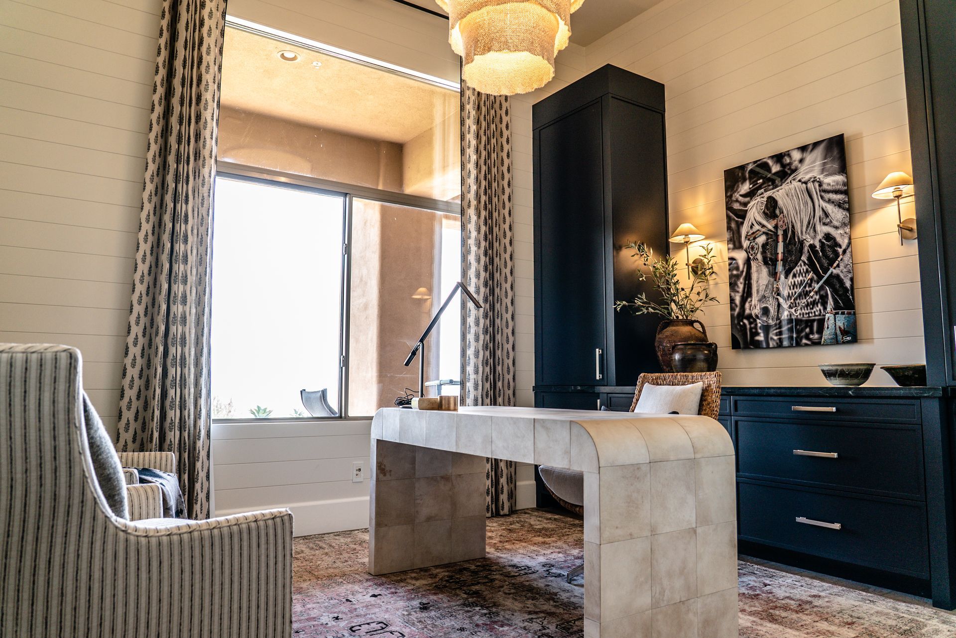 A home office with a desk , chair , and large window.