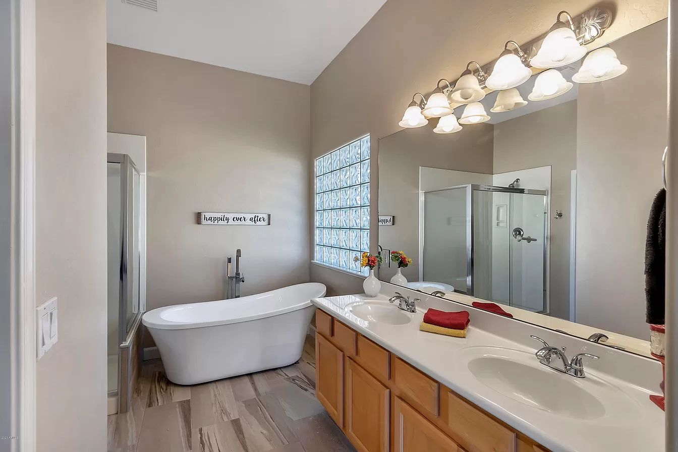 A bathroom with a tub, sink, and mirror.