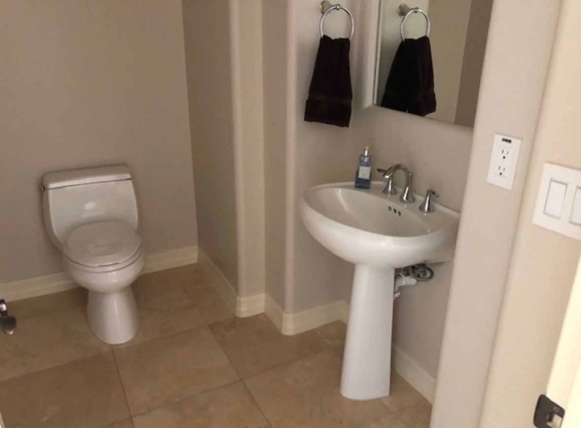A bathroom with a toilet , sink and mirror.