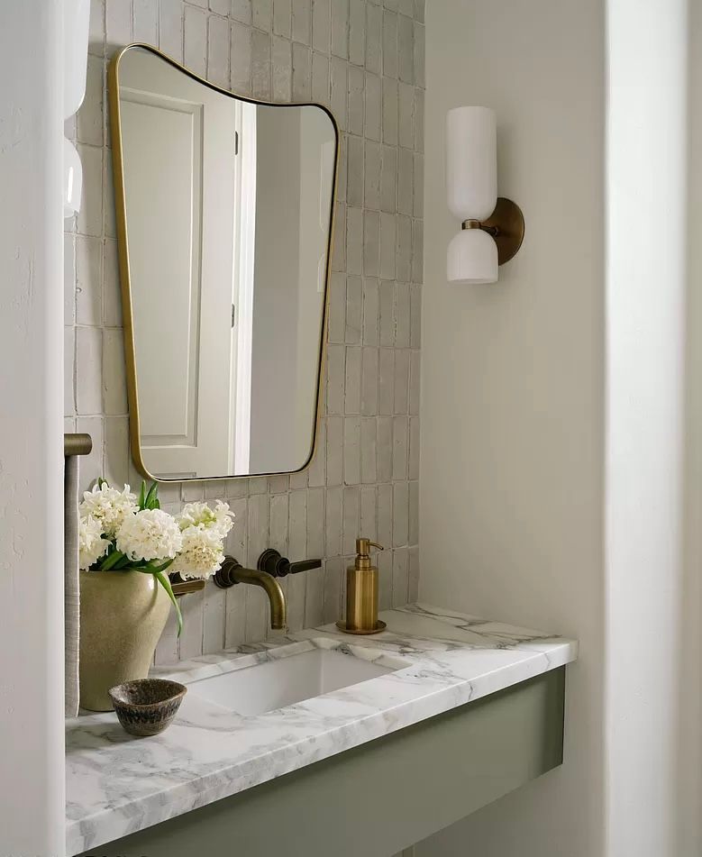 A bathroom with a sink , mirror and light.
