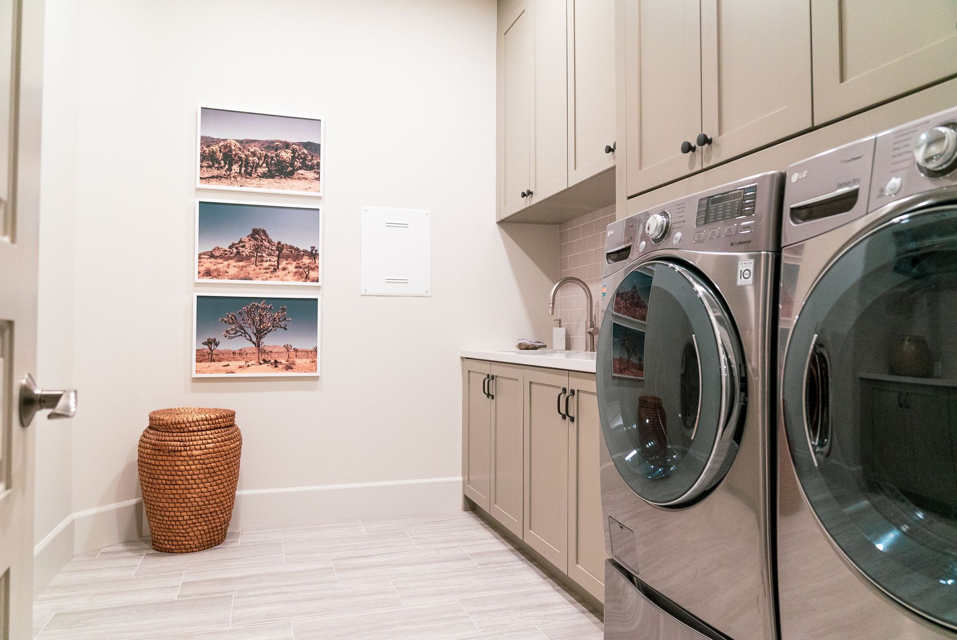 A laundry room with a washer and dryer and three pictures on the wall.
