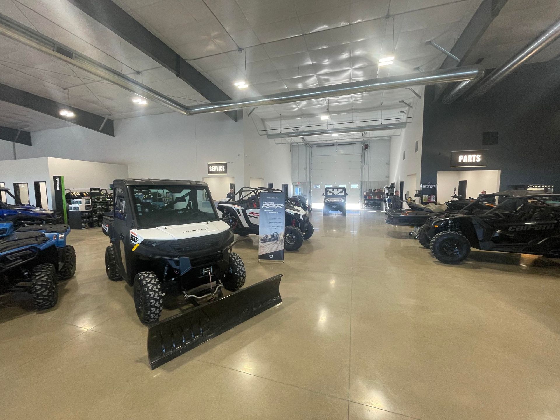 A showroom filled with lots of ATVs and a snow plow