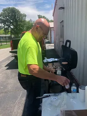a man in a neon green shirt is cooking food on a grill