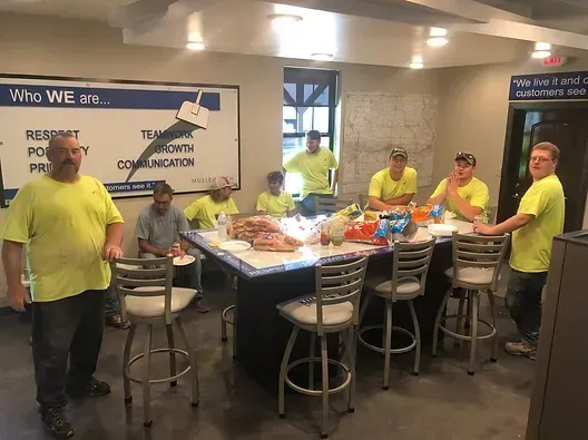 a group of men are standing around a table in a room 