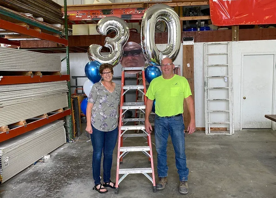 a man and a woman are standing next to a ladder with balloons on it 