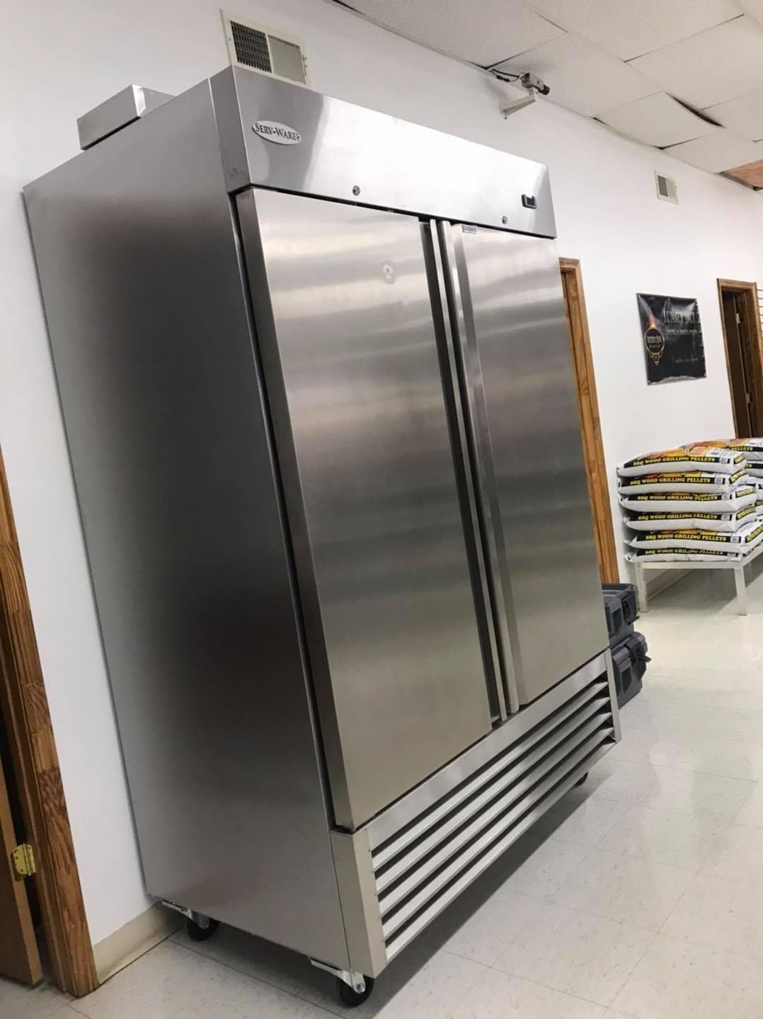 Stainless steel commercial refrigerator with double doors in a room.