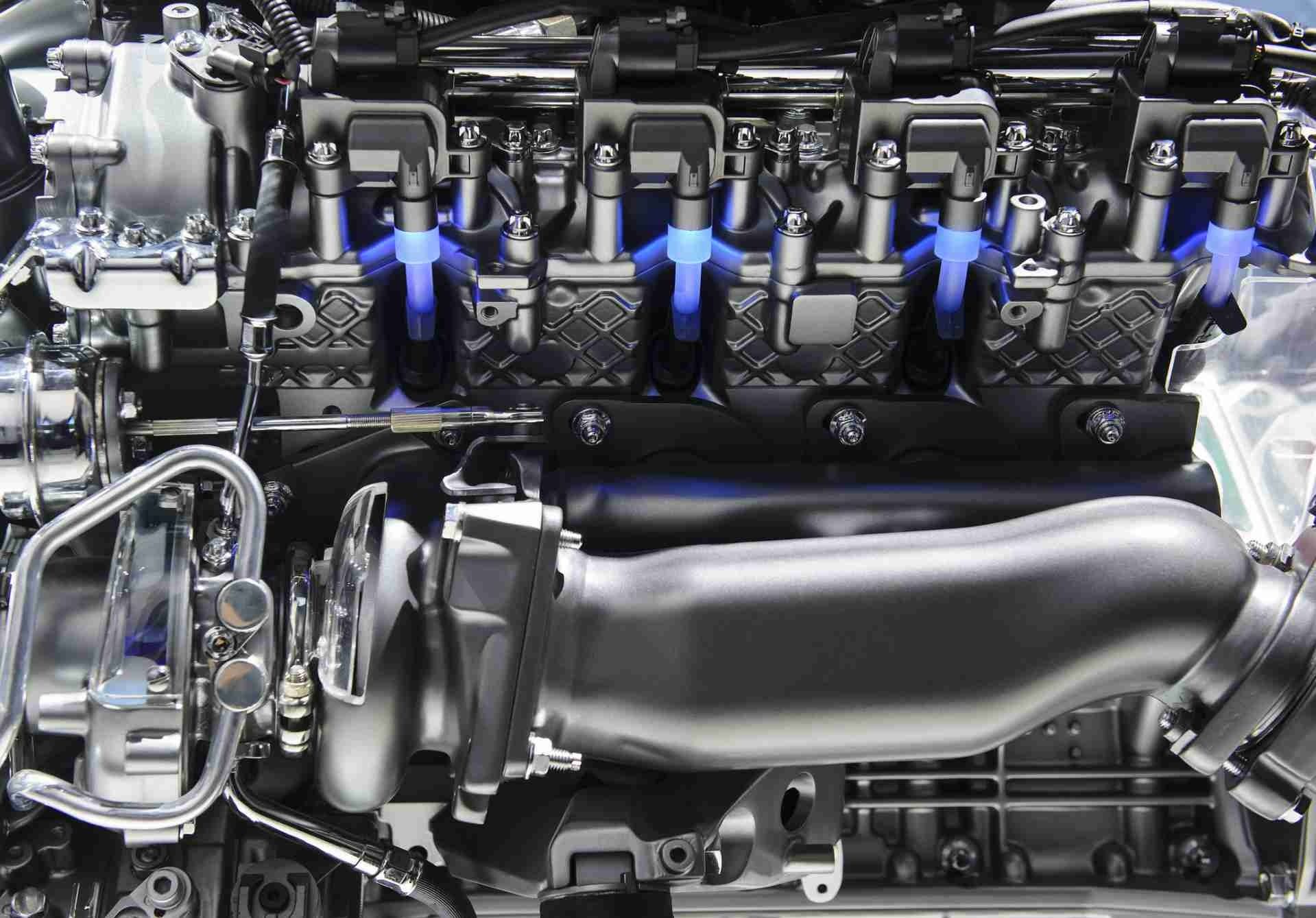 Close-up of a car engine with shiny black and silver components and blue hoses