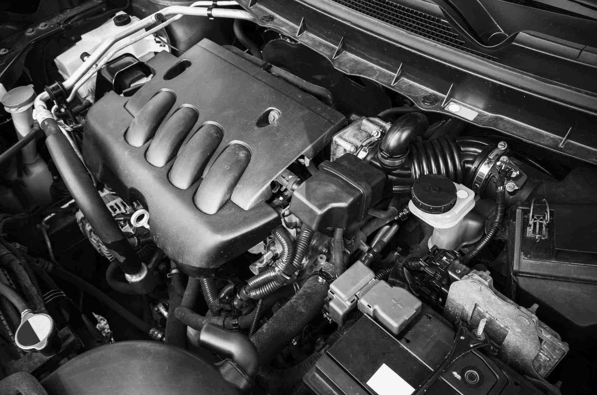 Car engine bay with visible engine cover, air intake, and battery compartments