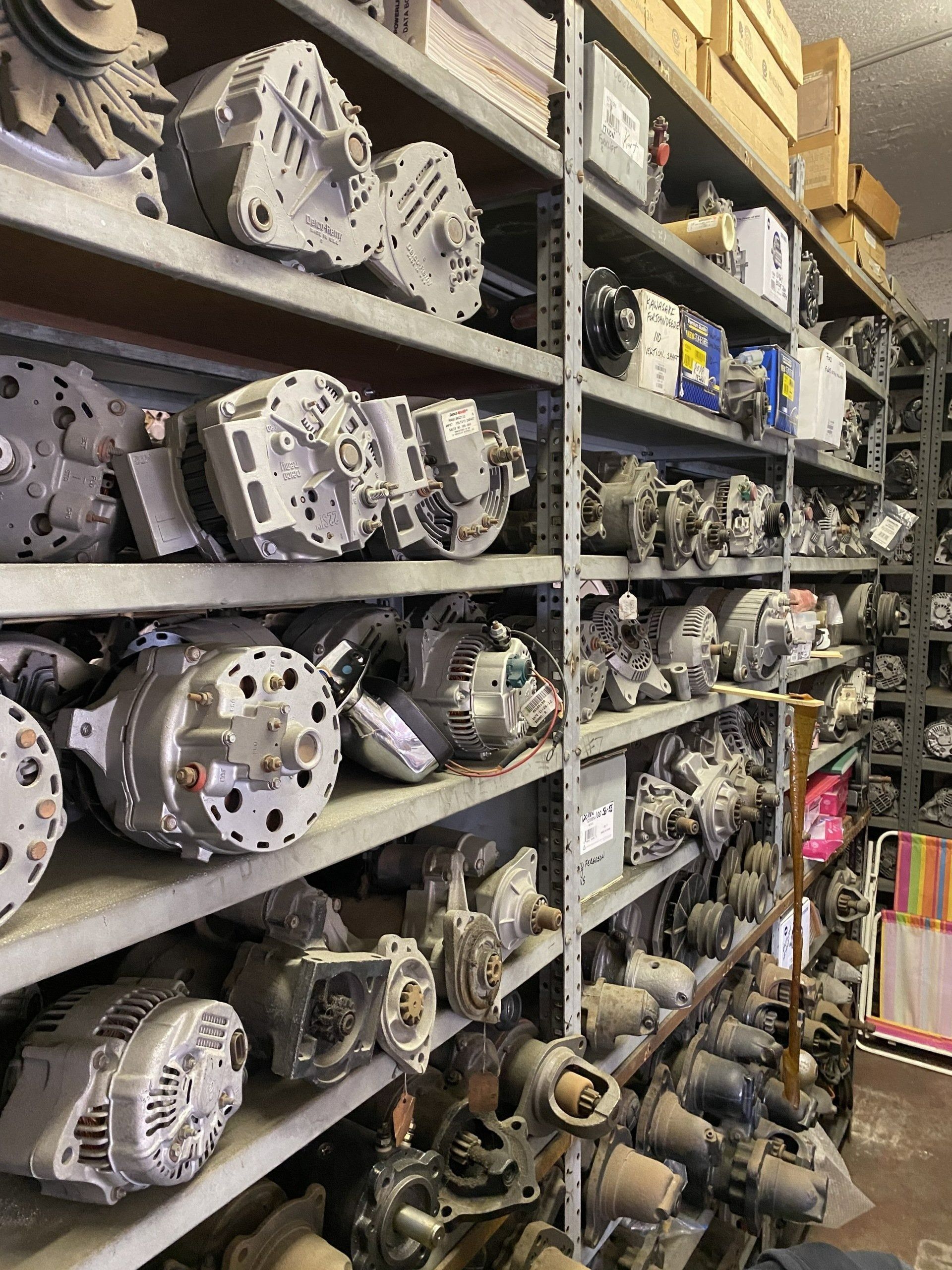 Shelves packed with rows of metal automotive parts in a warehouse storage area