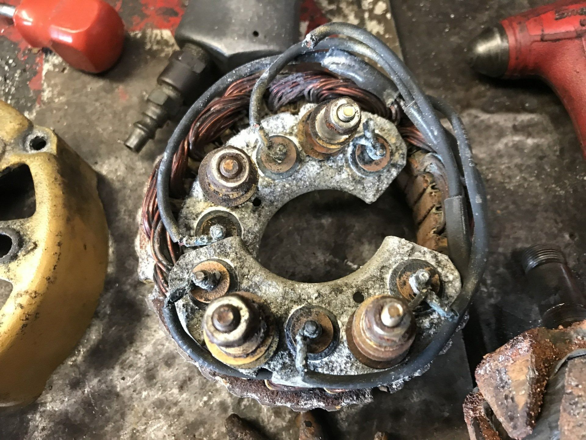 Close-up of a corroded electrical connector with tangled wires on a workbench, surrounded by tools