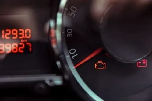 Car dashboard close-up showing illuminated warning lights and gauges at night