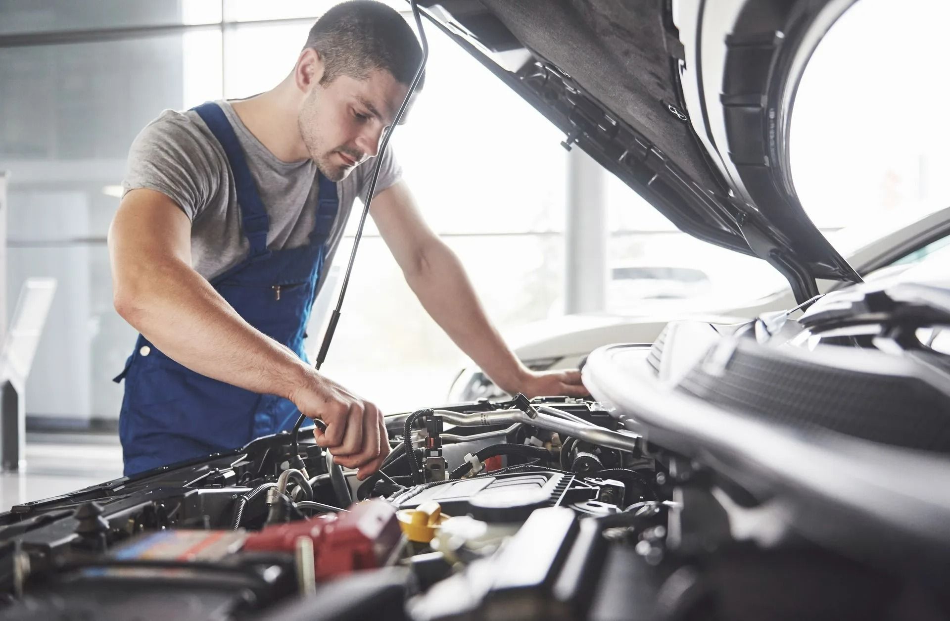 Mechanic inspecting engine in a bright auto repair shop, with hood open