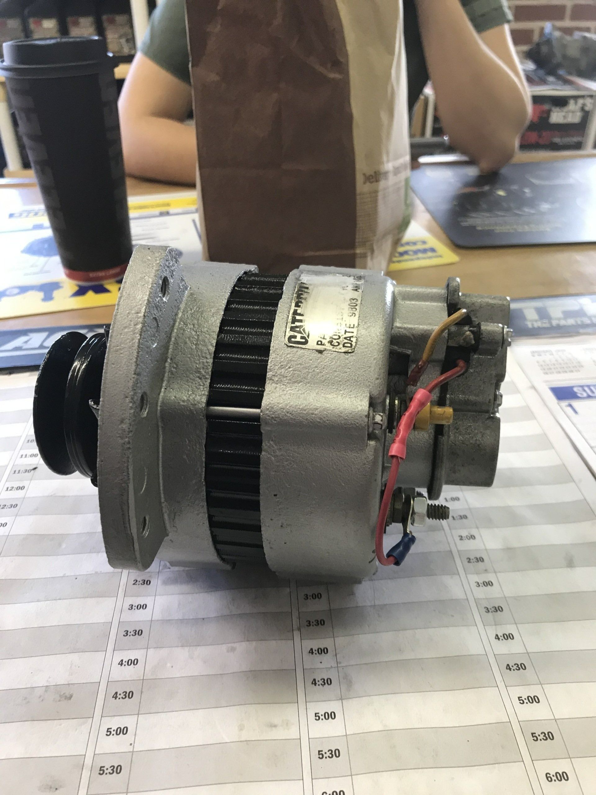 Small silver and black motor on a table, with red and black wires attached.