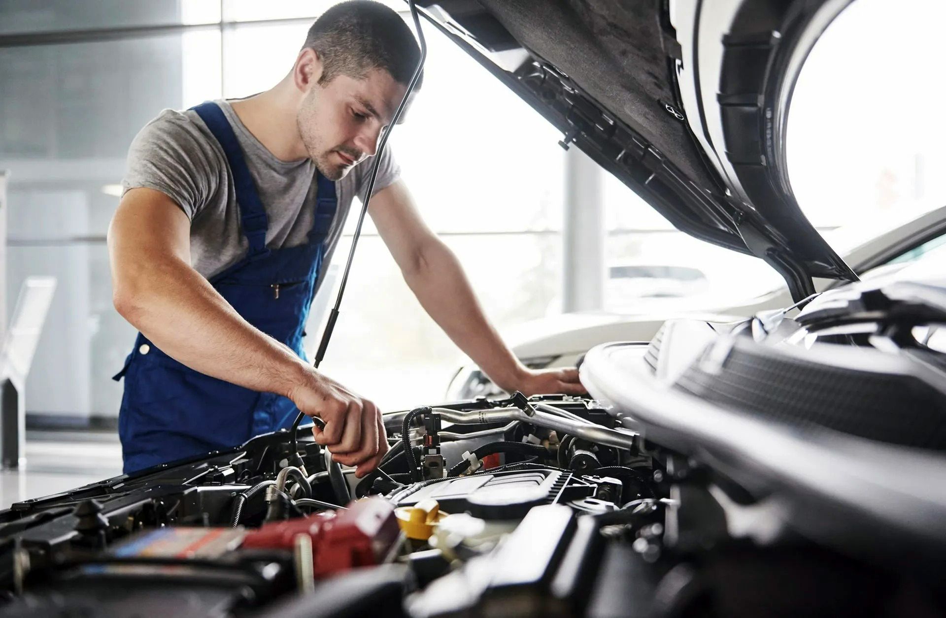 Mechanic inspecting an open car engine in a garage