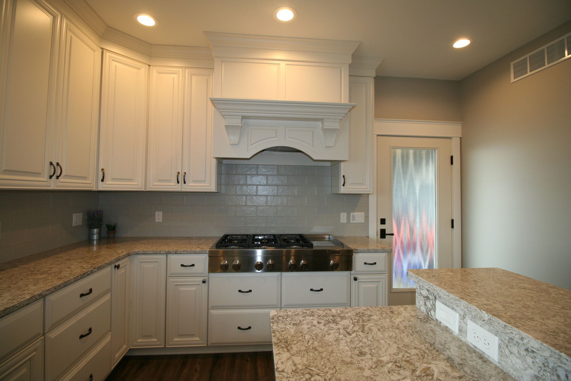 White kitchen with granite countertops and stainless steel range.