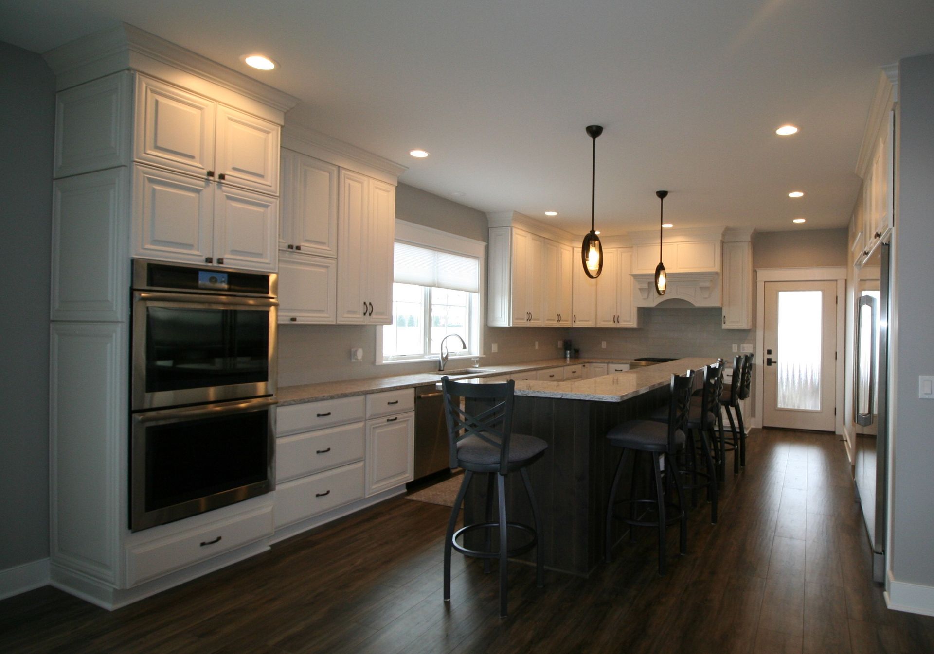Modern kitchen with white cabinets, dark island, and stainless steel appliances.