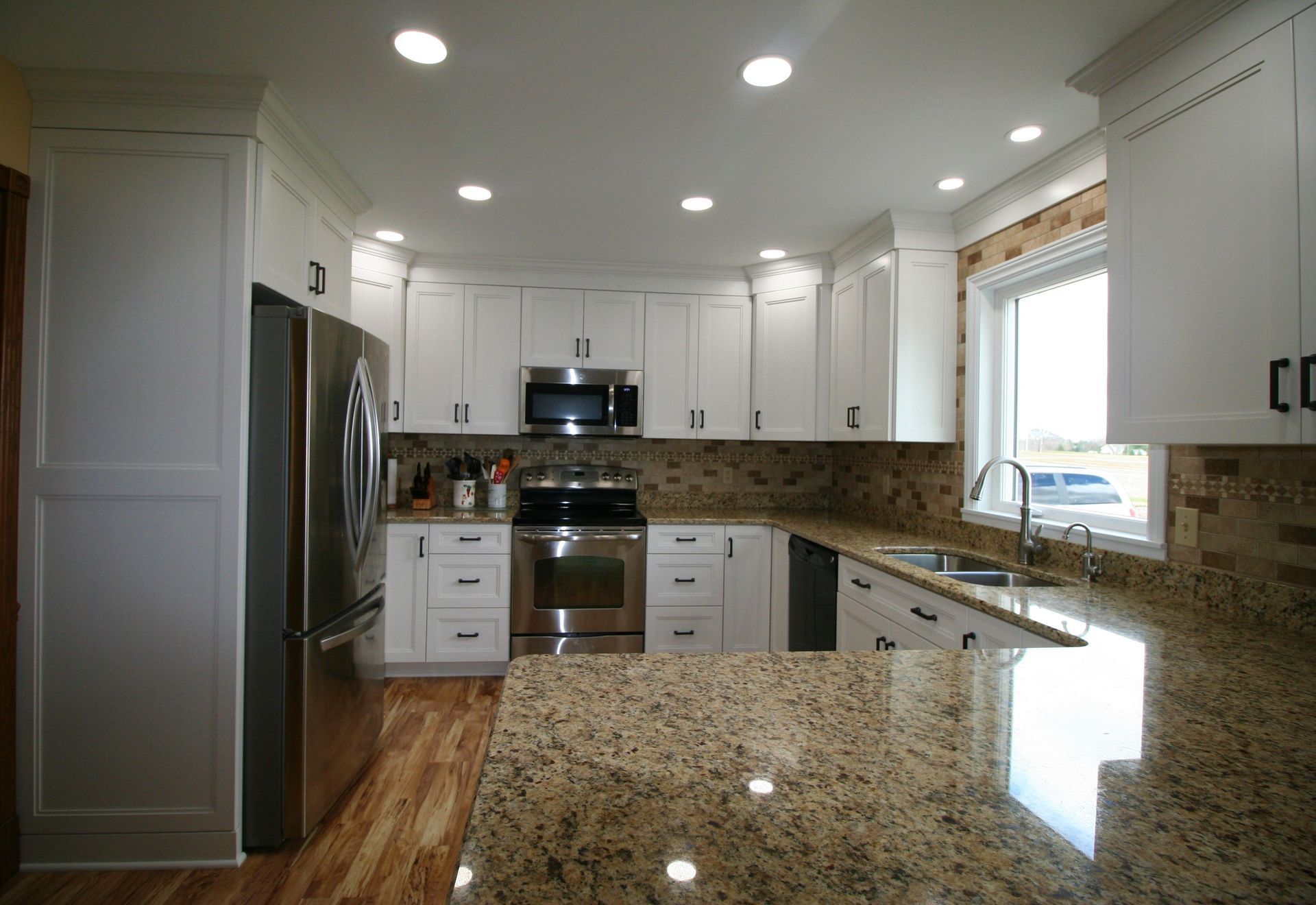 Bright kitchen with white cabinets, stainless steel appliances, and granite countertops.