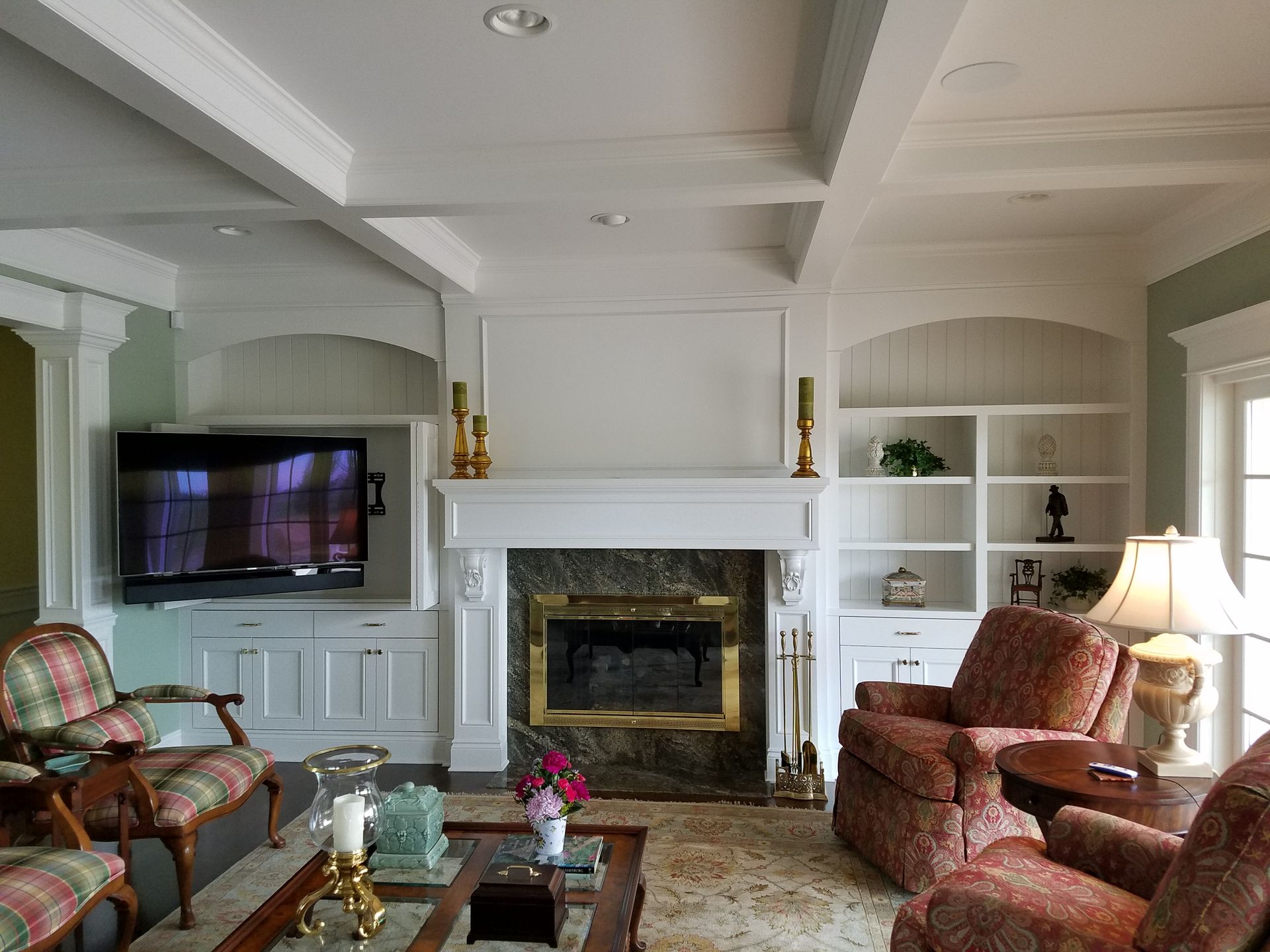 Living room with fireplace, built-in shelves, TV, two armchairs, and a coffee table.