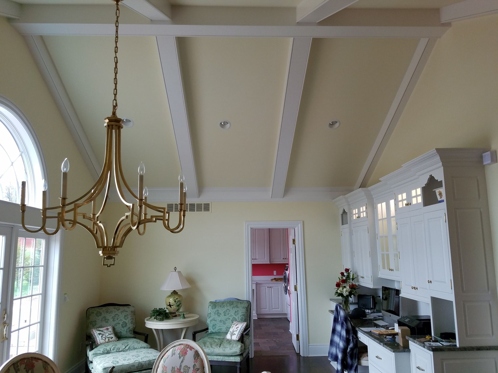 Dining room with vaulted ceiling, gold chandelier, and white cabinets.