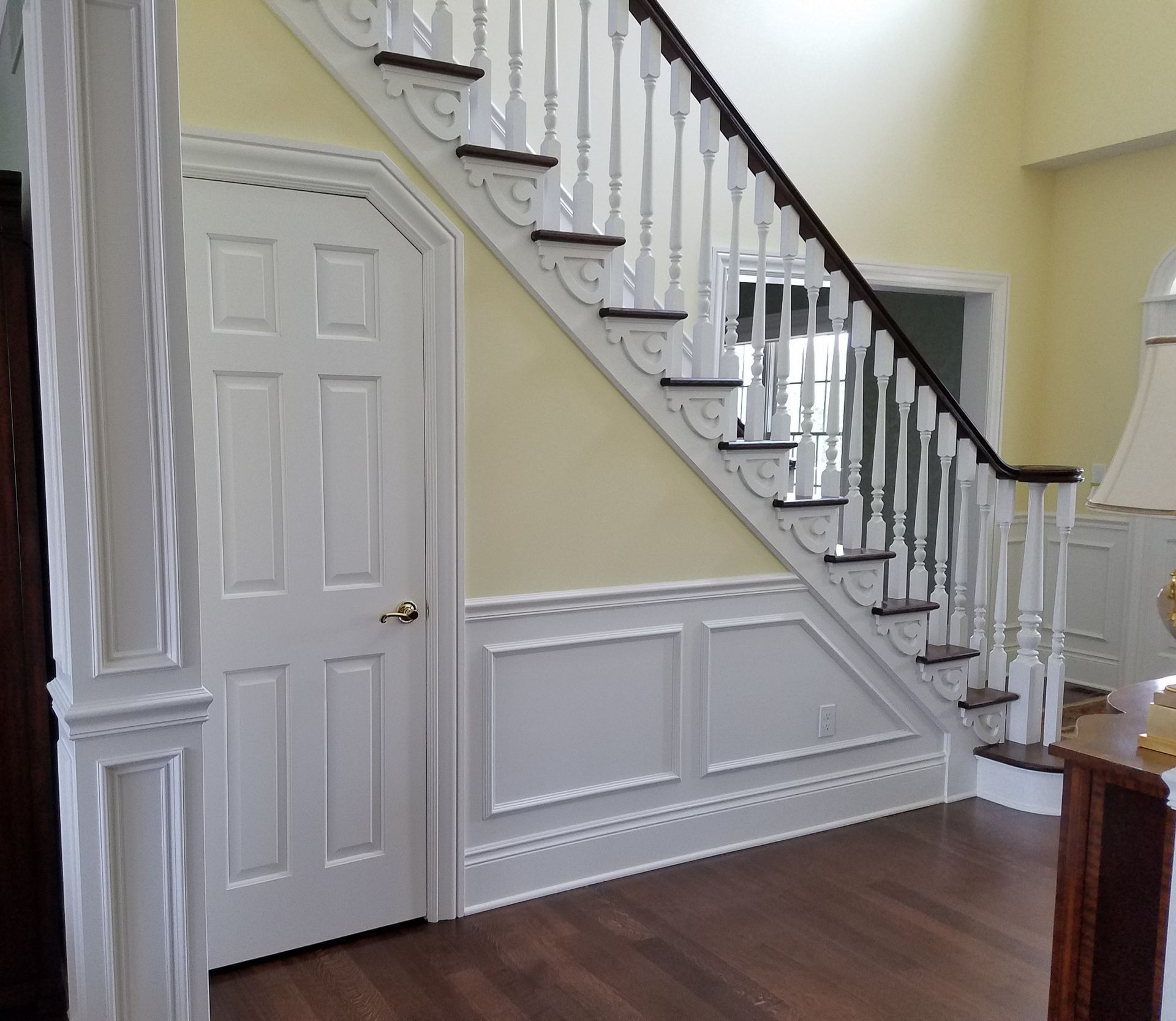 Interior view of a staircase and doorway with white trim and dark wood steps and railing, set against yellow walls.