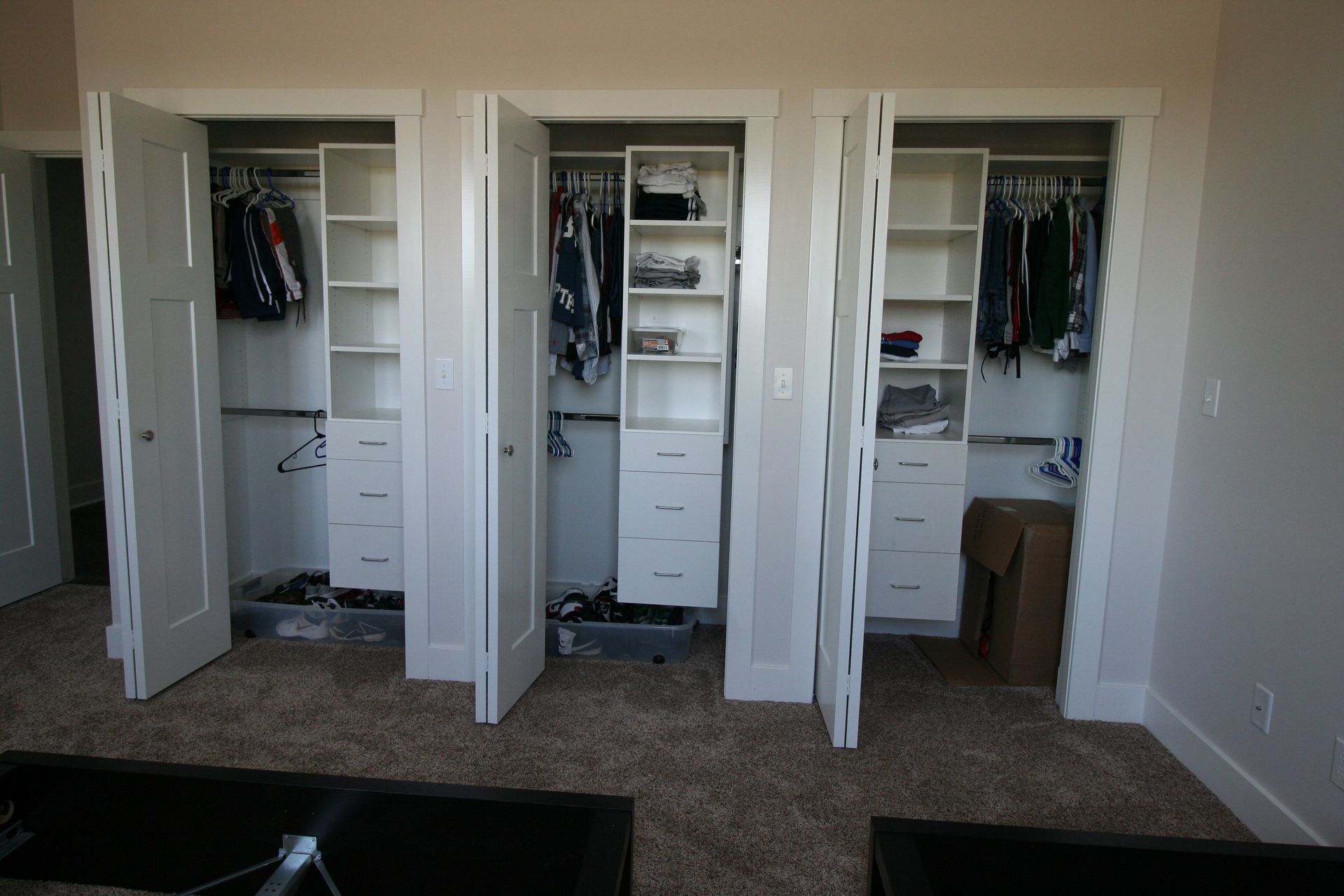 Three white closet doors open to reveal organized shelving and hanging clothes.