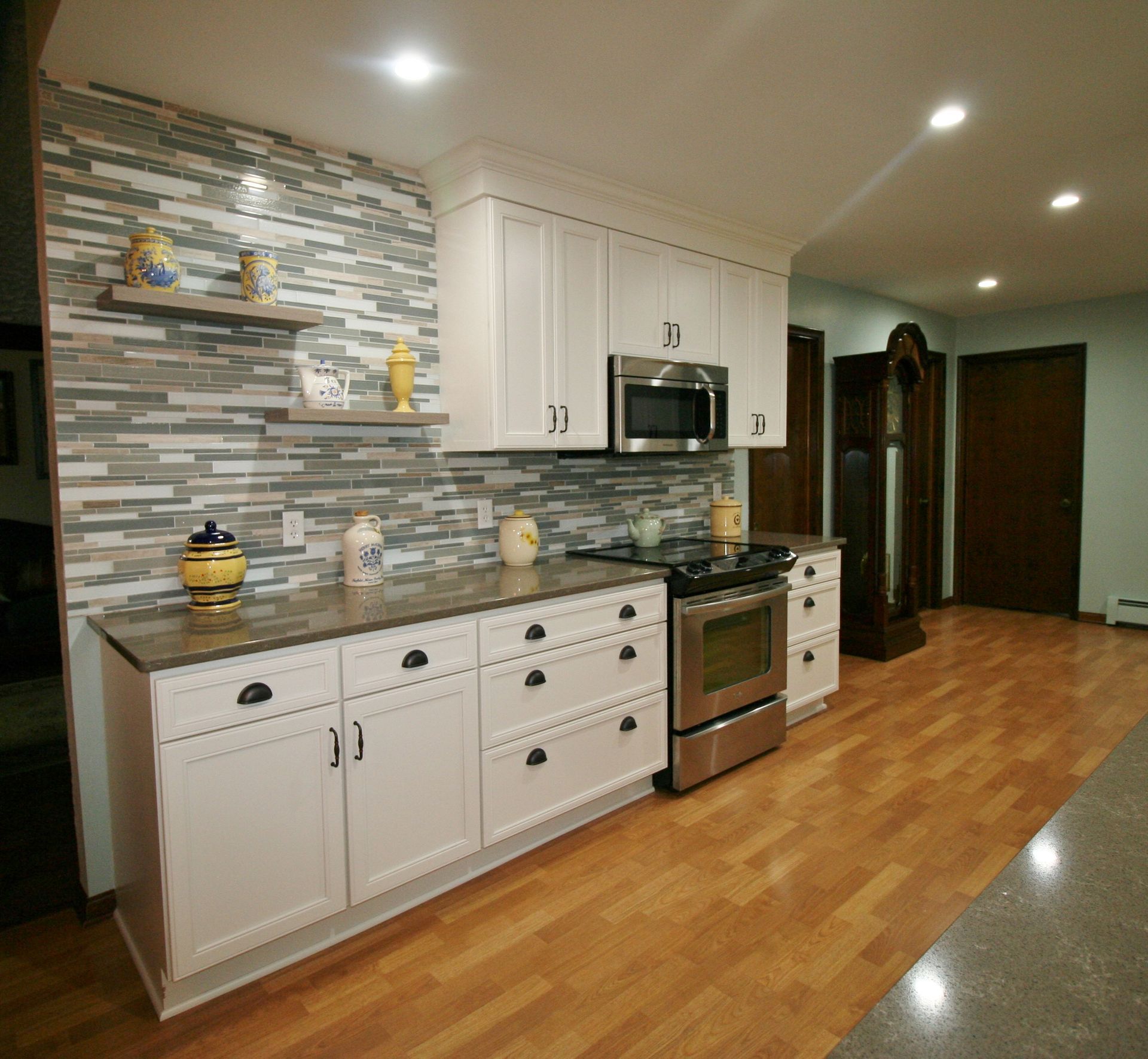 Modern kitchen with white cabinets, stainless steel appliances, and stone accent wall.