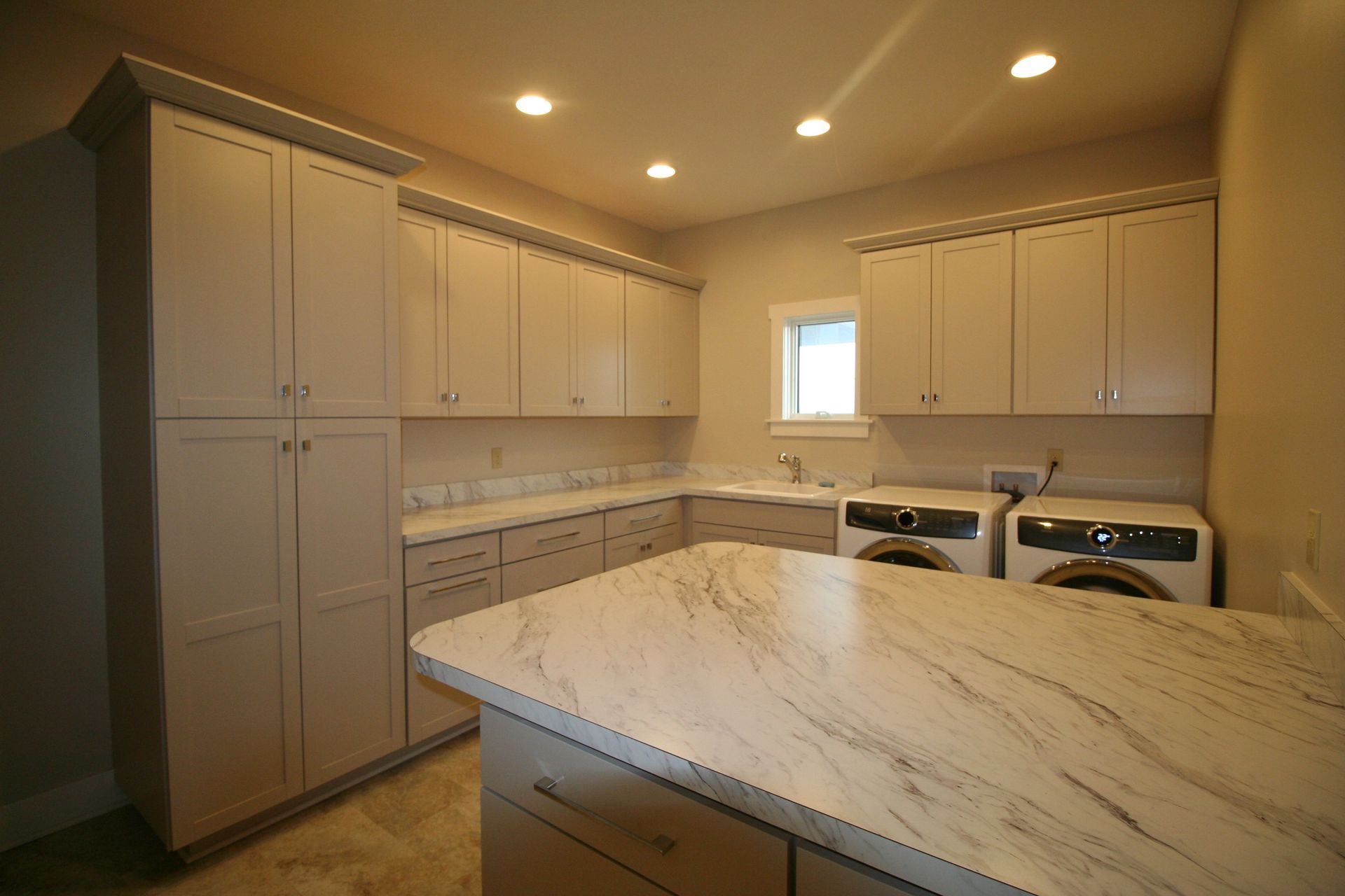 Laundry room with light gray cabinets, white countertop, and washer/dryer.