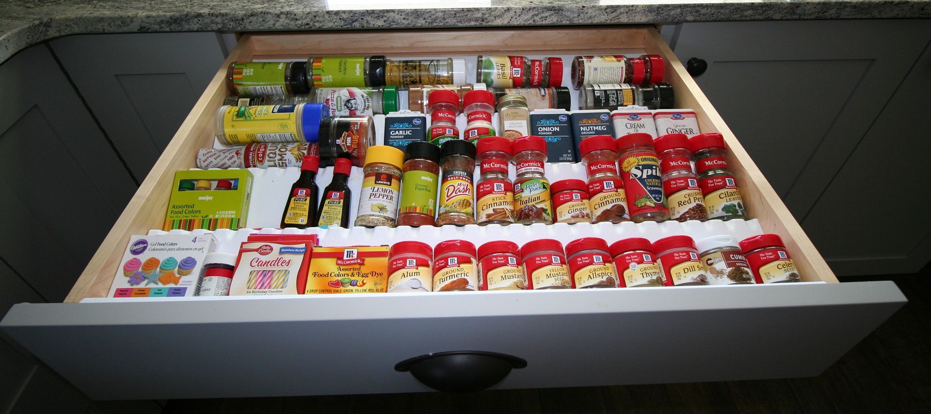 Open kitchen drawer filled with spices, sauces, and baking mixes.