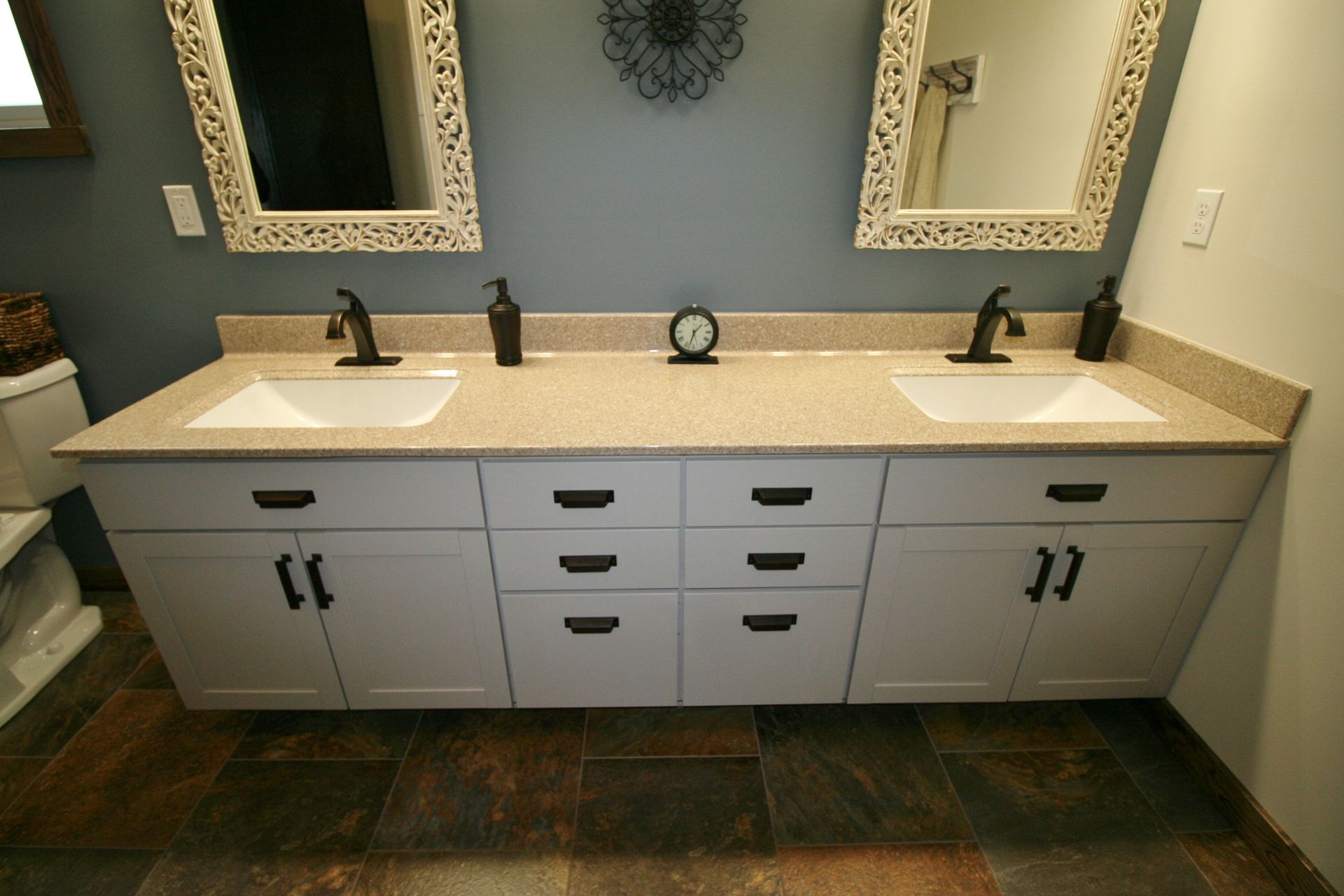 Double-sink vanity with white cabinets, speckled countertop, and black fixtures in a modern bathroom.