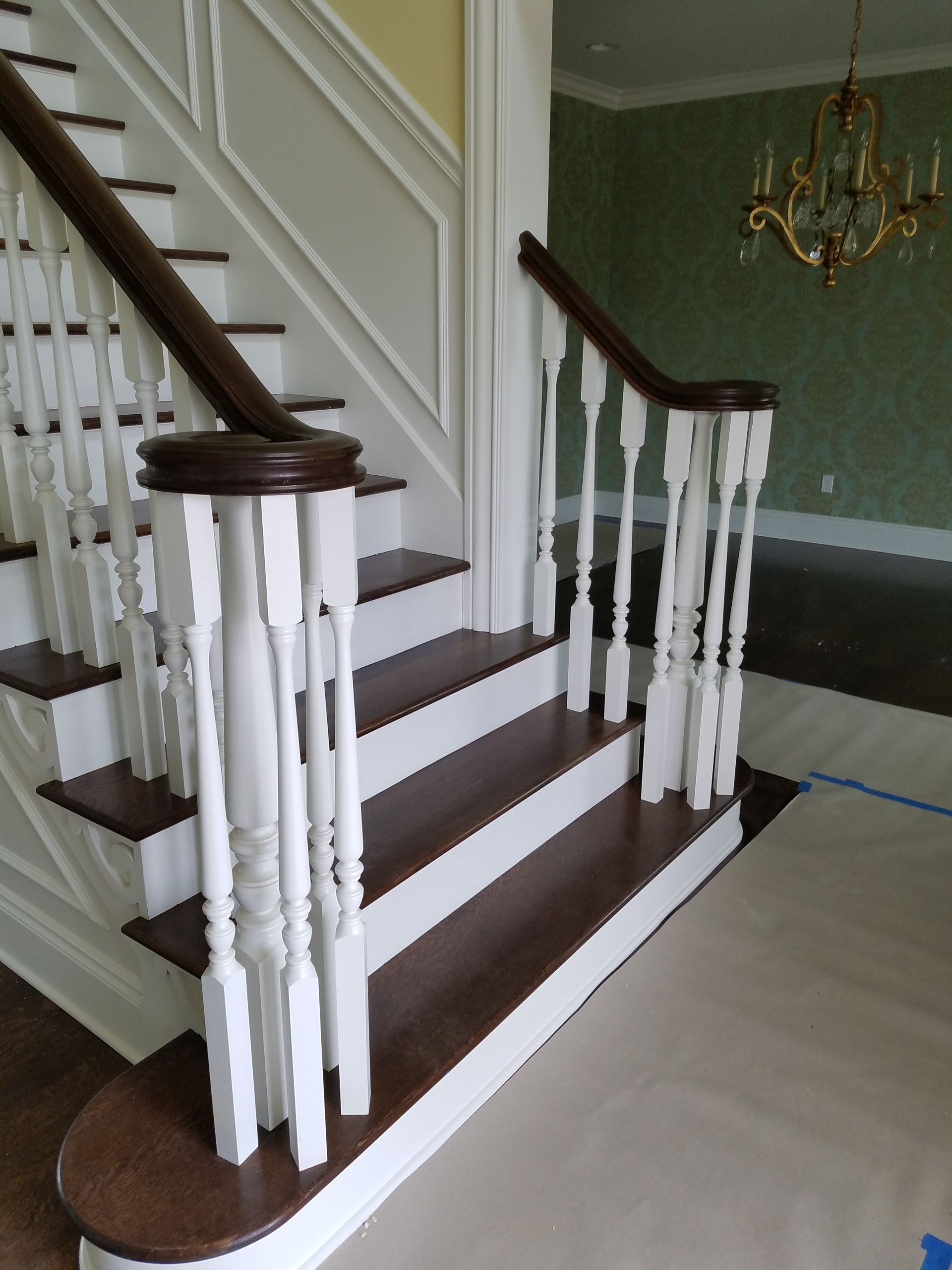 Staircase with brown steps, white railing, and dark wooden handrail, leading upstairs.