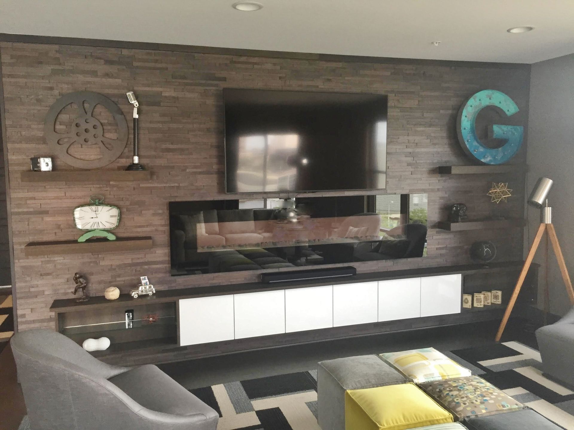 Living room with a wooden accent wall, shelves, large TV, and decor.