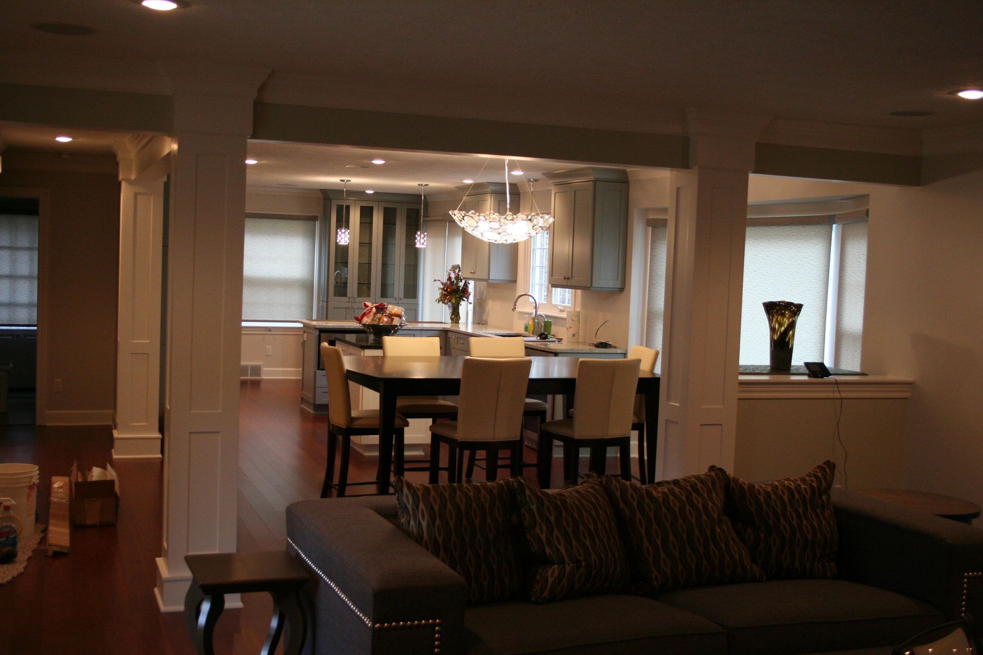 Open-concept kitchen and dining area with modern blue cabinets, dark table, and living room in view.