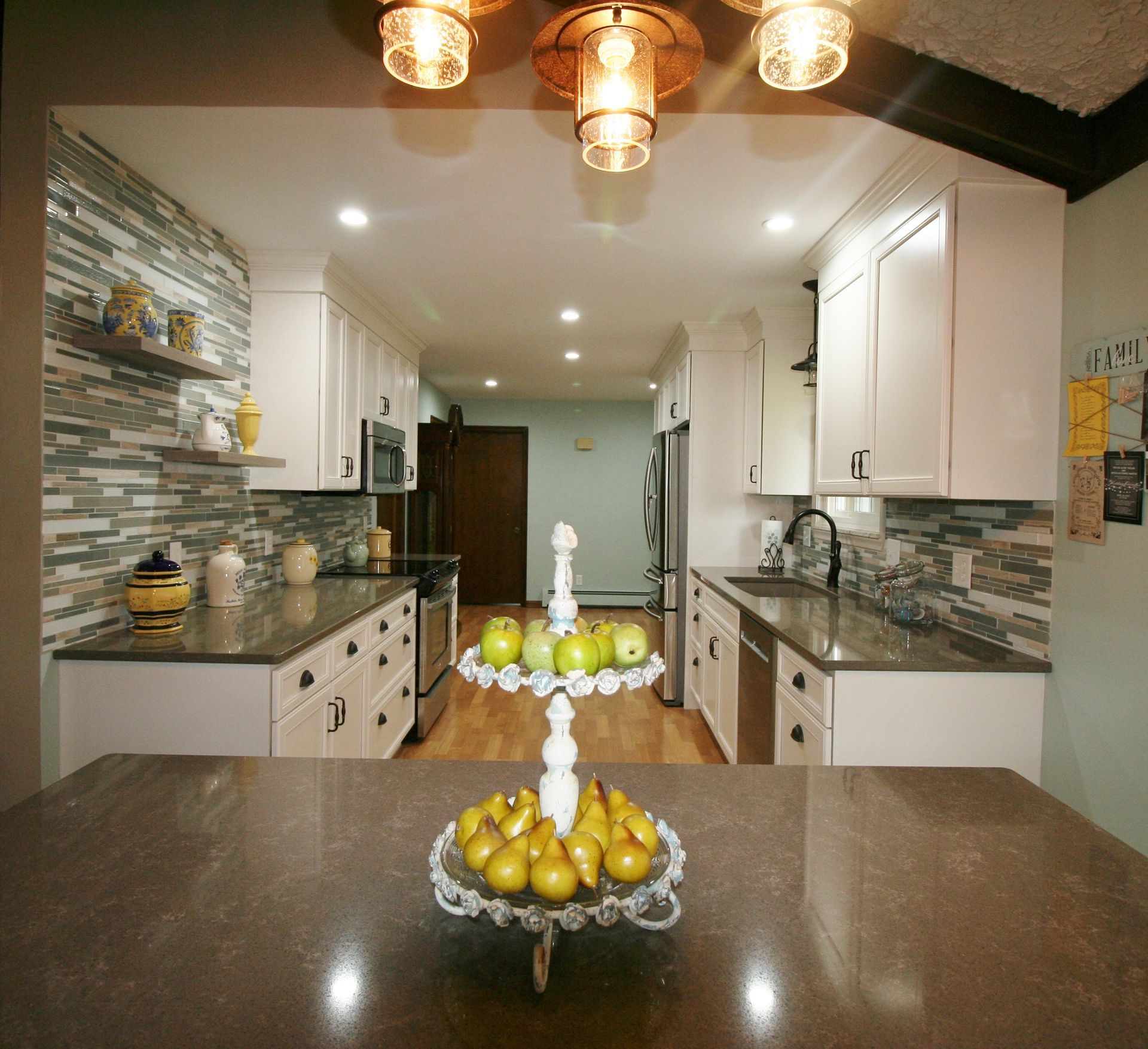 Kitchen with white cabinets, dark countertops, and a tiered fruit stand on the island.