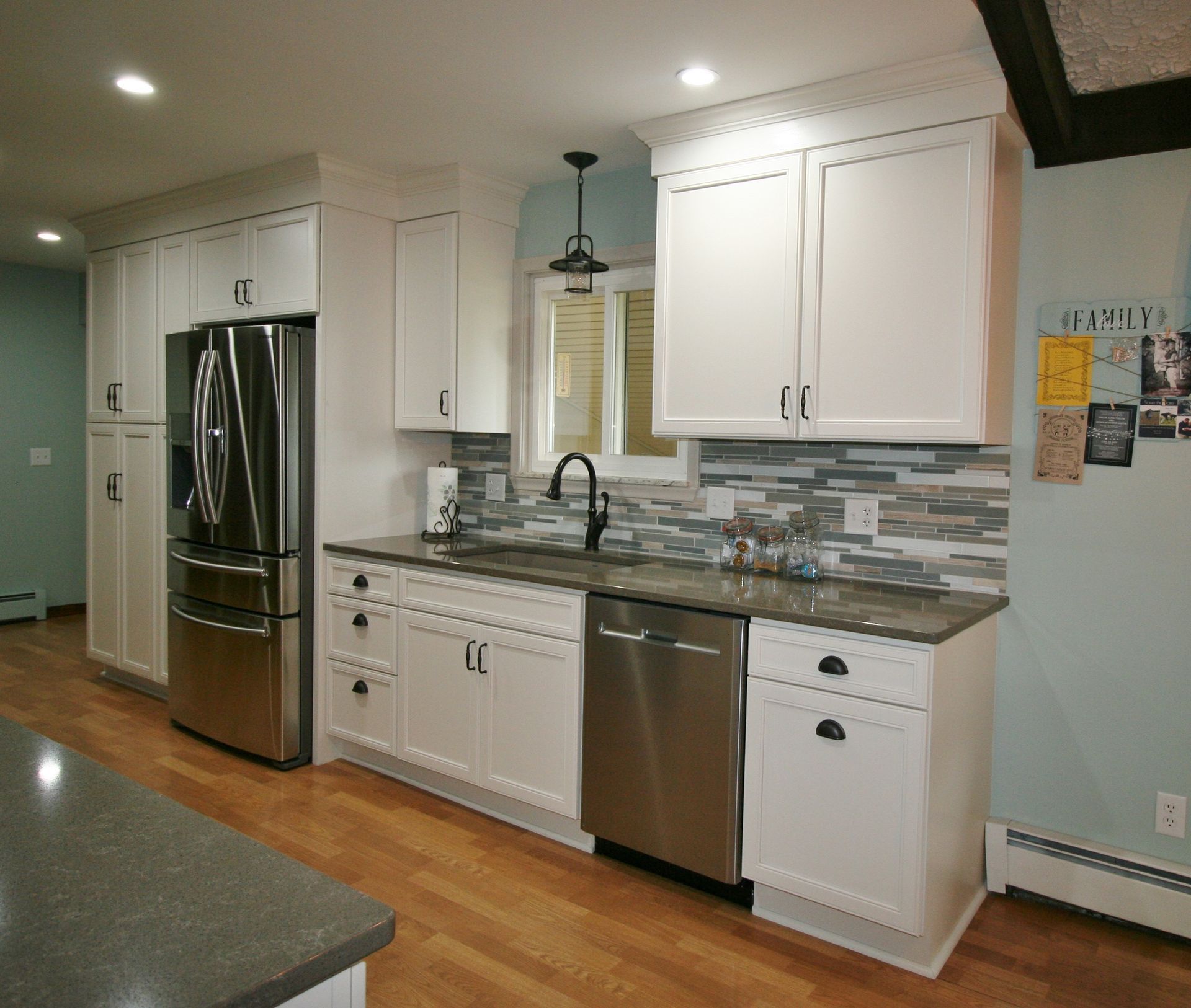White kitchen with stainless steel appliances, grey countertops, and a tiled backsplash.