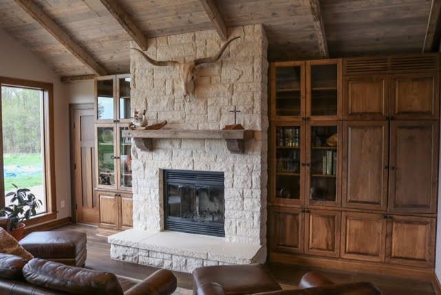 Living room with stone fireplace, wood cabinets, and longhorn skull decor.