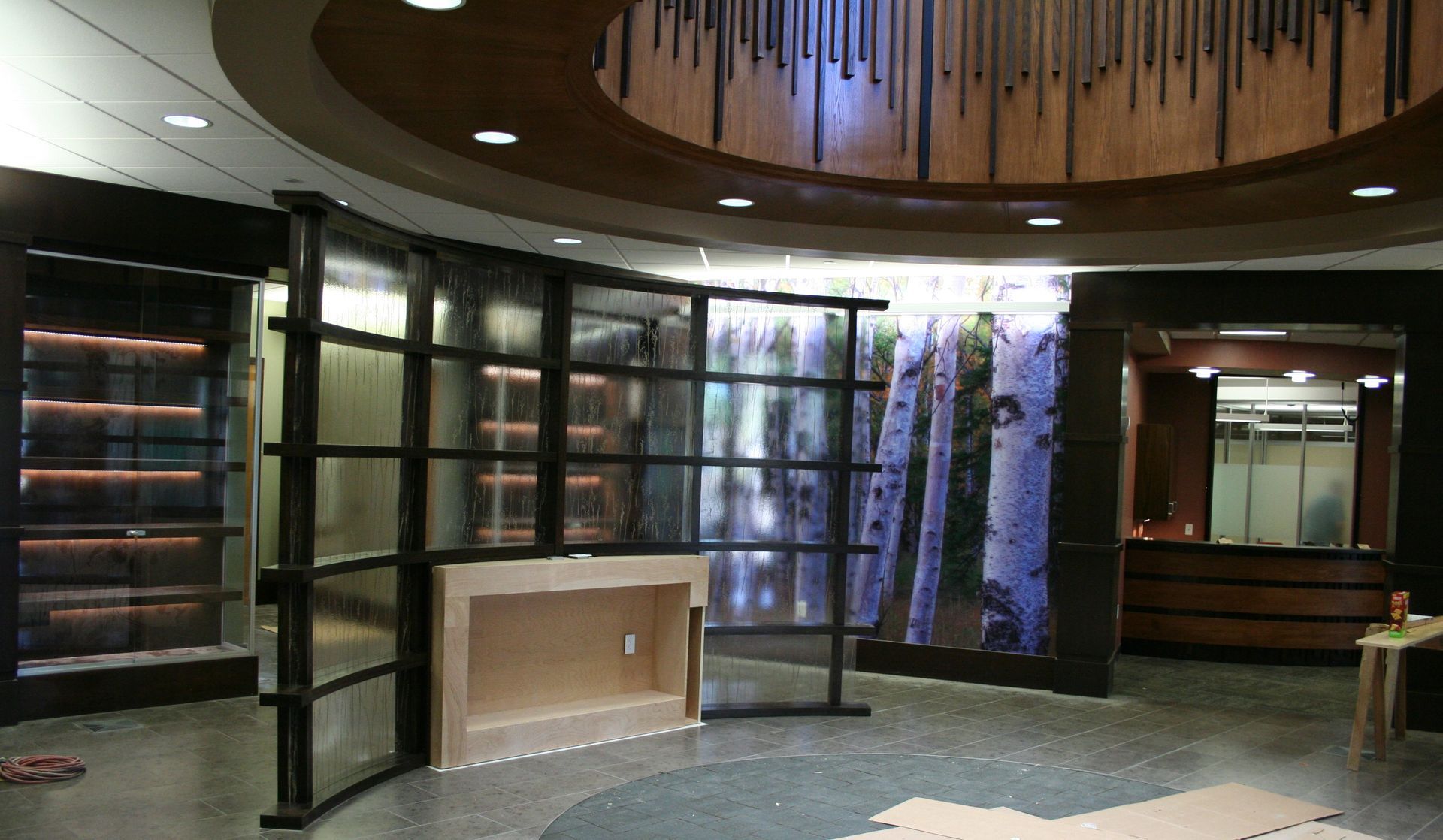 Curved glass wall with a forest mural, display shelves, and a reception area.