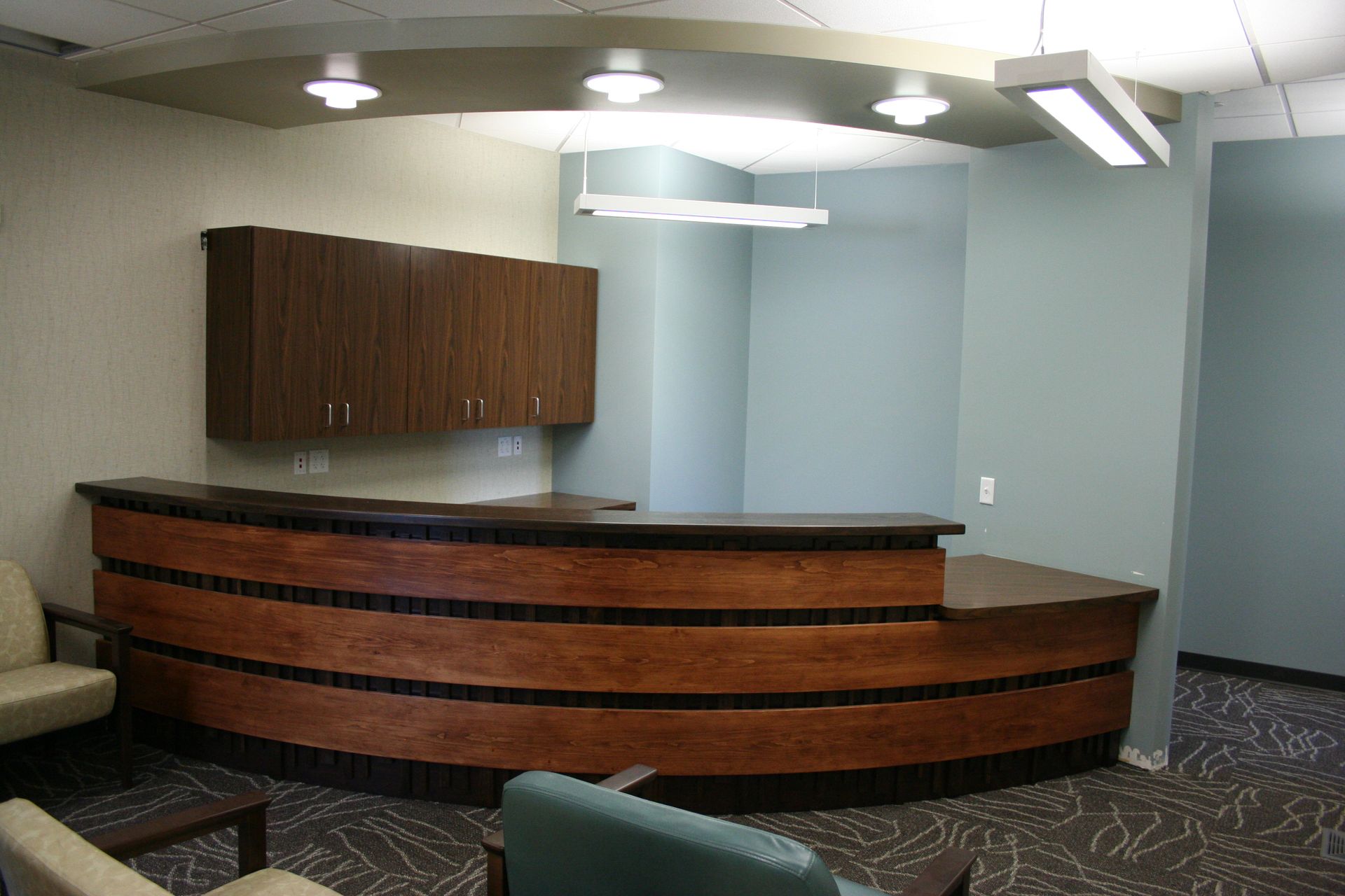 Reception desk in a waiting area with wood paneling and cabinetry, neutral colors.