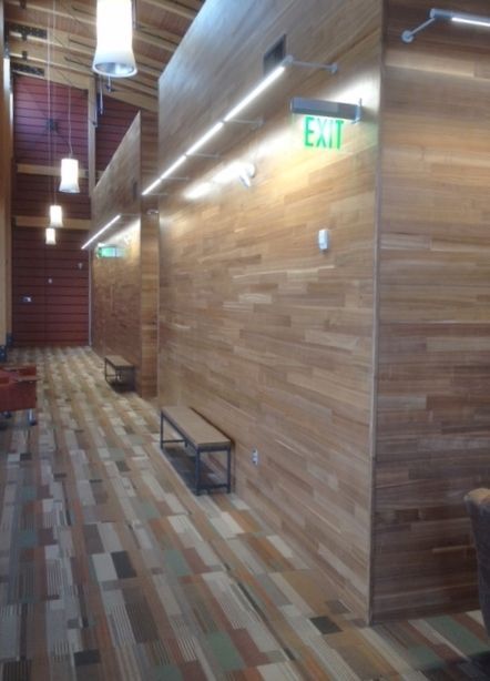 Hallway with wood panel walls, exit signs, benches, and a colorful patterned floor.