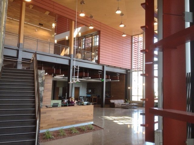 Interior of modern building lobby with staircase, reception desk, and upper level.