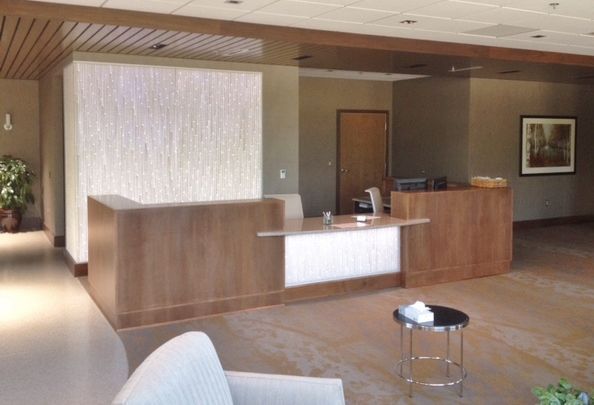 Reception area with wood reception desk and textured wall, neutral color scheme.