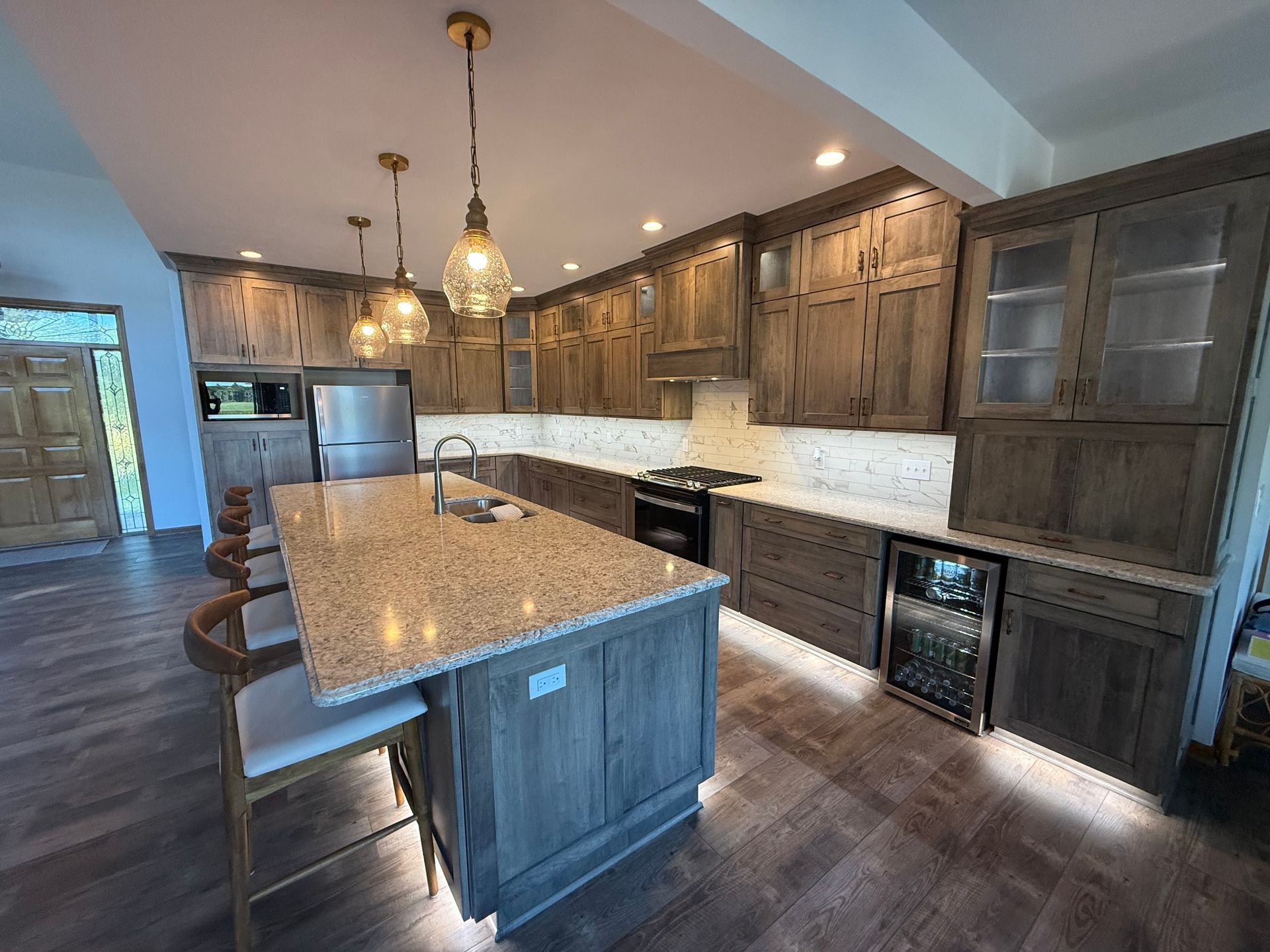 Spacious kitchen with gray cabinets, island with granite countertop, stainless steel appliances, and pendant lights.