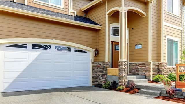 Beige house with white garage door, stone entryway, and steps.