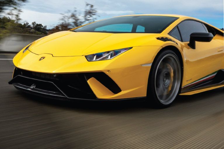 A yellow lamborghini huracan is driving down a road
