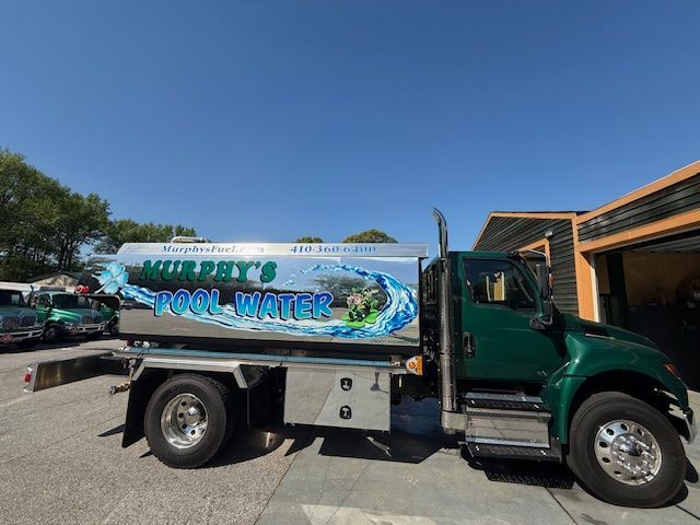 A Murphy's pool water truck is parked in front of a garage.