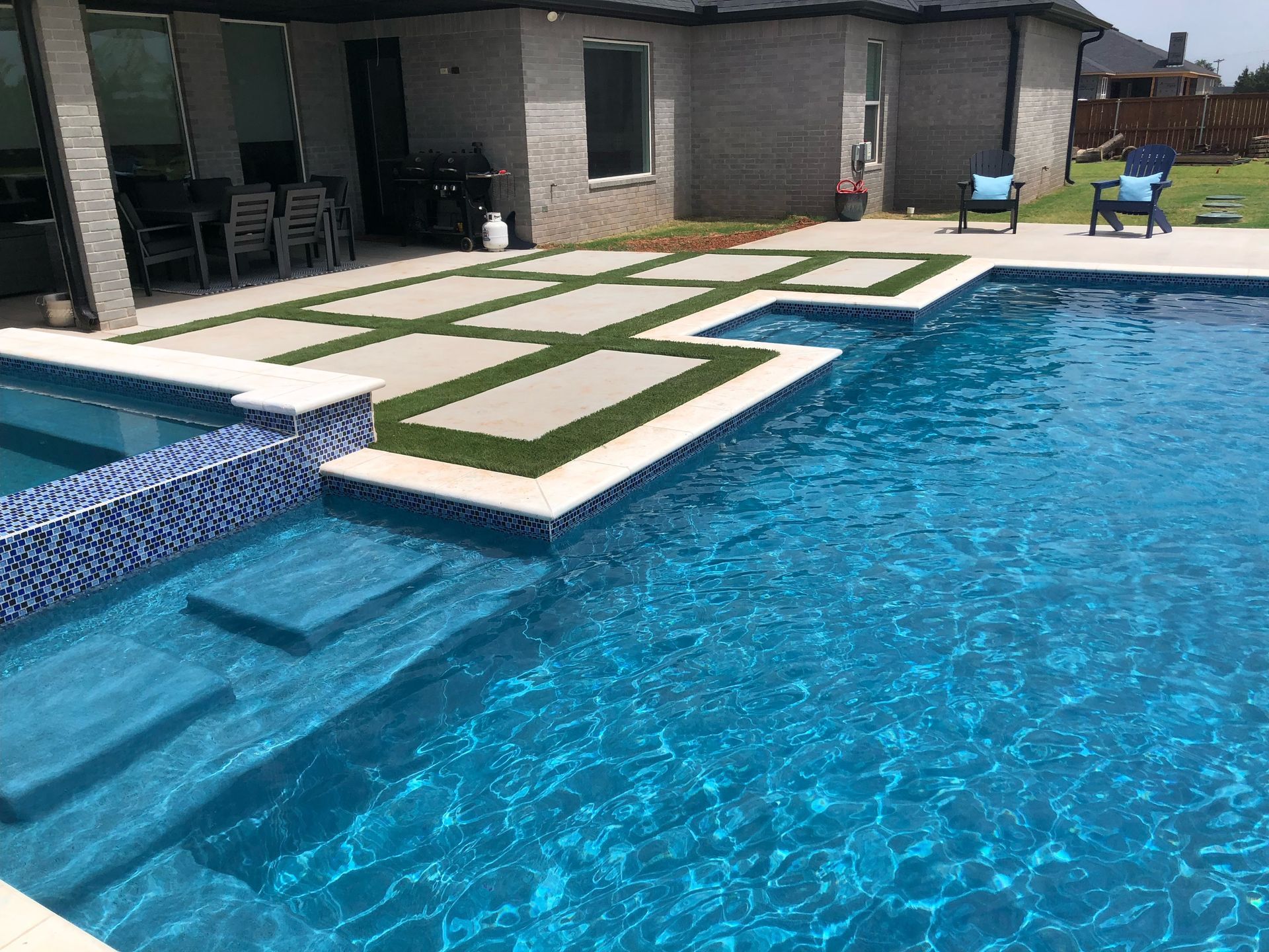 a large swimming pool with stairs leading to it in front of a house