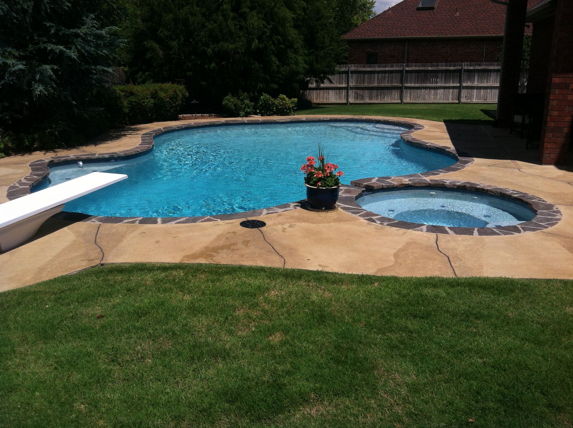 a large swimming pool with a diving board and a hot tub